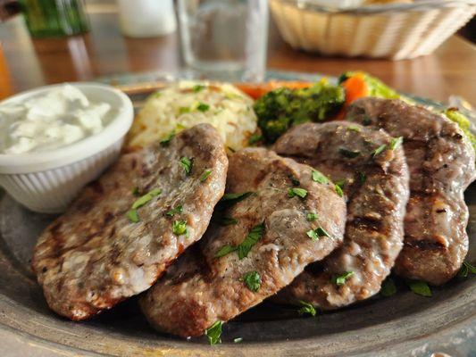 Char-grilled beef and lamb patties with rice pilaf, sautéed vegetables, and cacok sauce