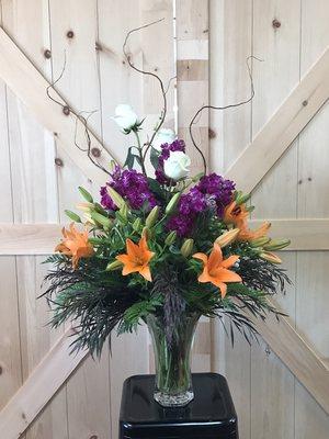 Gorgeous floral arrangement with orange lilies, purple stock and white roses.