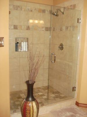 Beautiful tumbled stone shower with frameless glass door.