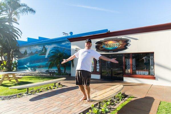 Bill Stewart, always laughing and having fun at Stewart Surfboards. Practice your cross-step on our handmade custom surfboard benches!