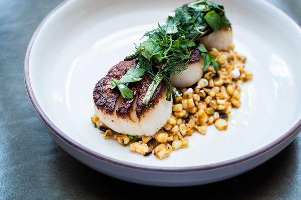 Flint's scallops on a bed of charred corn salad feature smoky, savory, Mediterranean seafood flavors that melt in your mouth.