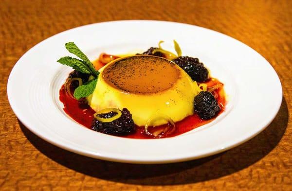 Vanilla custard topped with caramel and served with sweetened blackberries and candied lemon peel.