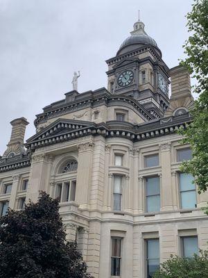 Blind Liberty stands in front of clock.