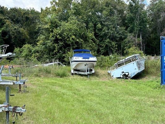 Rotting, rusted plane and boat on either side of boat with blue cover