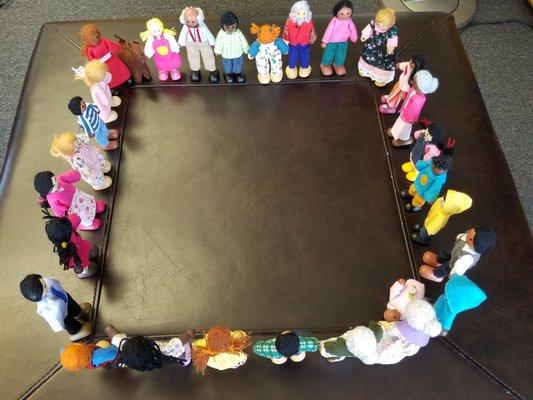 Playhouse dolls showing diversity, arranged in a square holding hands