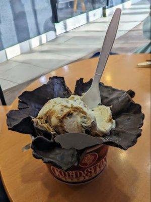 Cake batter ice cream with peanut butter and chocolate chips in a a chocolate dipped waffle bowl.