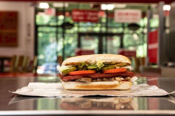 A Five Guys hot dog sits on the counter in a Five Guys restaurant.