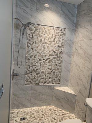 Custom tile installation with corner seat in a small bathroom and designed to make the space look larger