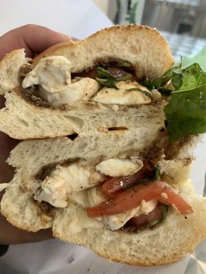 Caprese with salt and pepper on a fresh seeded braided roll.