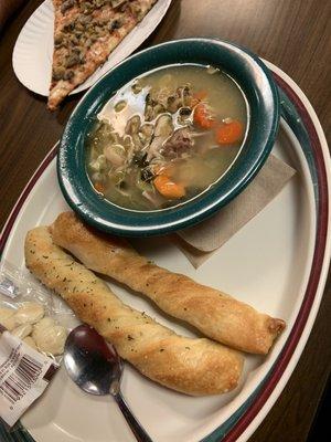 Bowl of Italian wedding soup with breadsticks