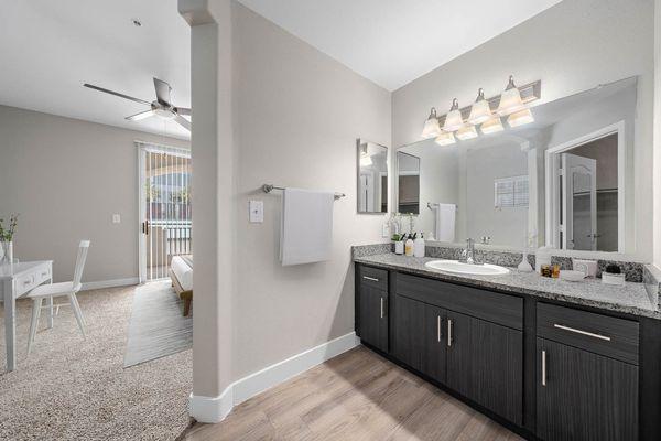 The Met furnished bathroom with large mirror, light fixtures, hardwood floors