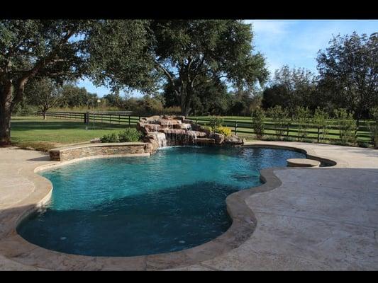 A natural free form shaped pool with moss rock boulder waterfall.