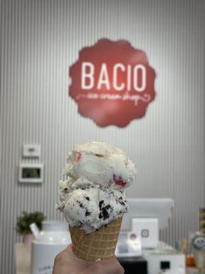 Waffle cone with 1 scoop of cookies and cream and strawberry cheesecake