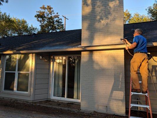 A candid photo of John helping us clean the gutters while I was trimming a scrub nearby.