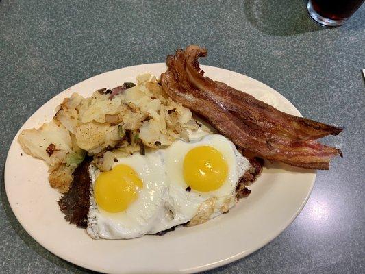 Sunny side up eggs over corned beef hash, home fries and bacon