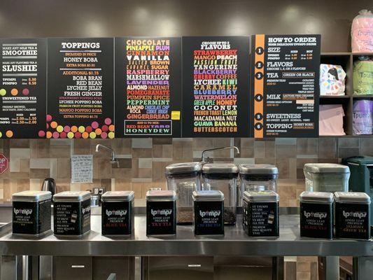 Selection of tea in black canisters, and partial menu above