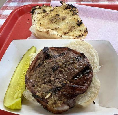 Garlic peppered beef tenderloin sandwich with a pickle on the side.