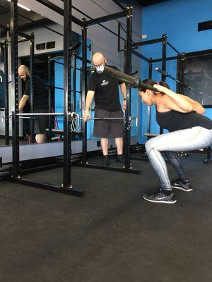 Moises teaching the barbell squat.