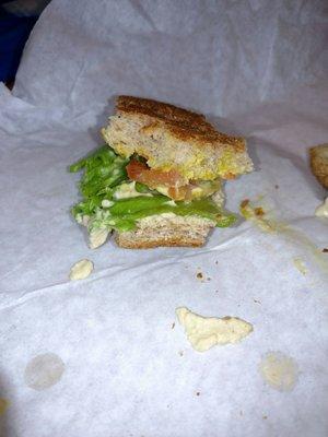 Portion of a vegetable sandwich on wheat bun