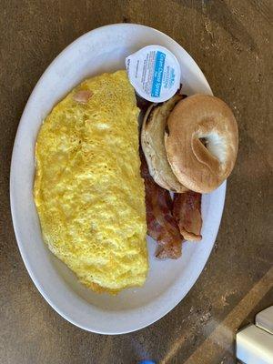 Ham and cheese omelette with a bagel and a side of bacon.