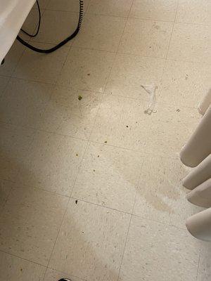 Floor next to patient bed with used medical glove, needle cap, food and poop.