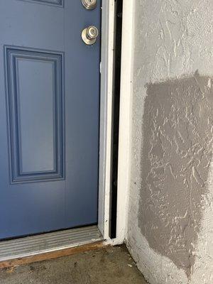 Sample paint color on stucco wall next to blue door