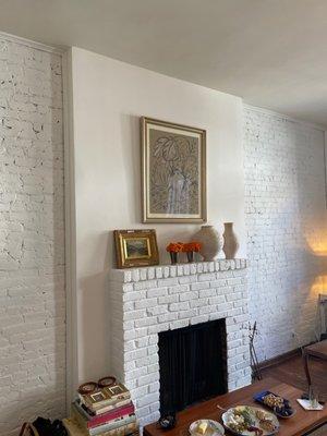 Brick wall and fireplace painted white.