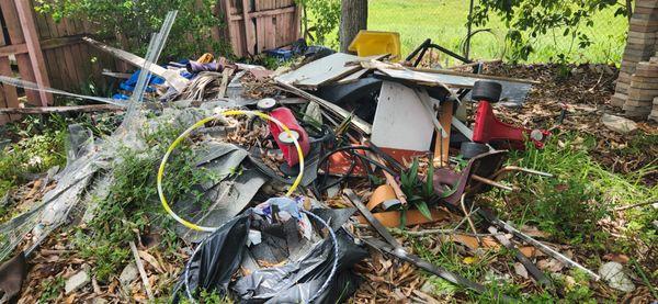 A full load of junk cleared from a customer's backyard, including yard waste, construction debris, and household items.