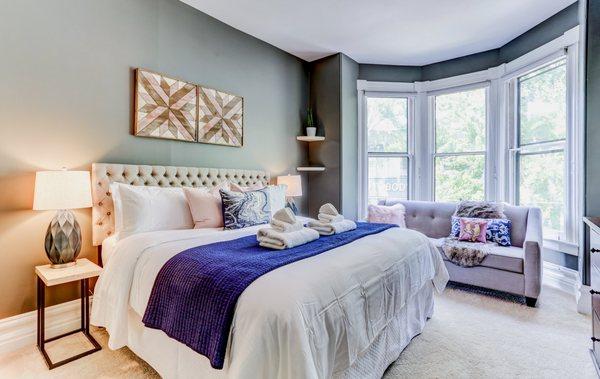 Staged master bedroom in white with green walls and blue and wood accents.