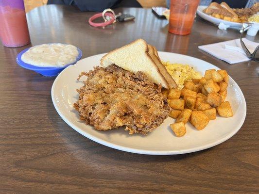 Chicken fried steak plate. A huge steak, hash browns, two eggs and two pieces of toast.