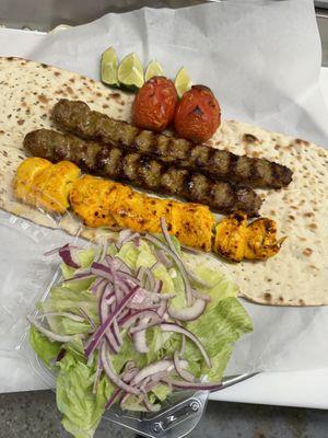 Ground beef and chicken tender kabobs on fresh bread with charbroiled tomatoes and salad