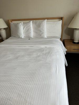 Bed with tag showing. Linens seem clean but very worn.