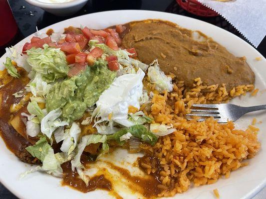 4 enchiladas, rice, beans, salad, guacamole and sour cream.