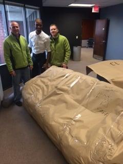 The Quality Manager and the movers wrapping a couch for long distance transport.