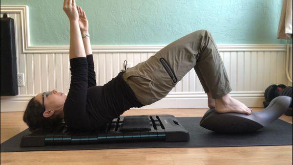 Back mobility laying on a device that gives instant auditory guidance, with feet on an unstable surface for an added layer of core work.