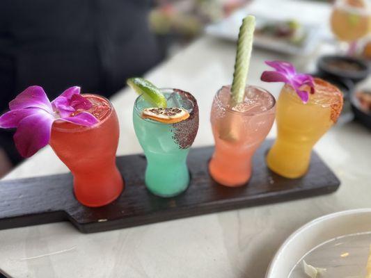 Seasonal Margarita Flight (rose petal [red], pineapple [blue], watermelon [pink], and mango [yellow]).