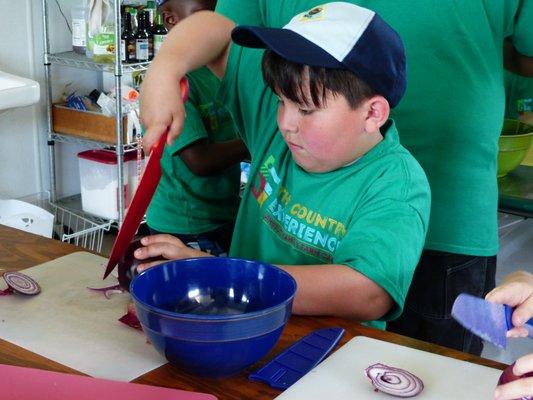 A student safely learns knife skills on a field trip to The Country Experience - a unique program we offer our lower elementary students.