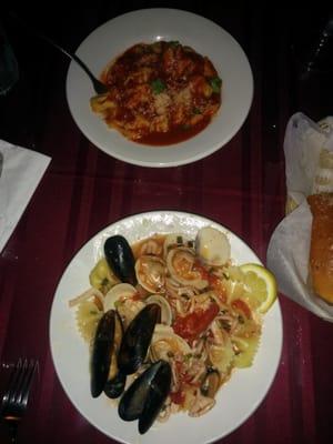 Front: calamari, clams, and mussels with bow tie pasta in a sauce Back: tortellini