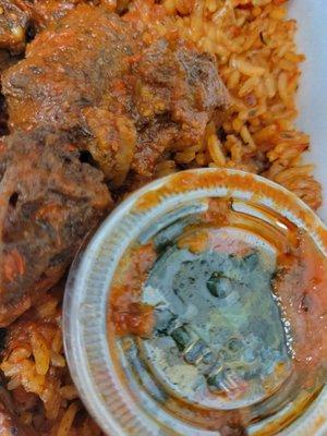 Jollof rice with chicken and beef. Spinach is in the plastic container