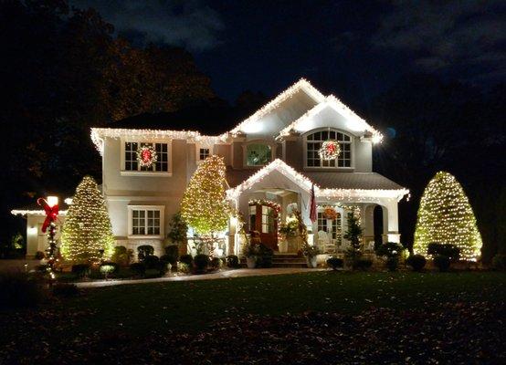 Ice lights incandescent adorn this beautiful home on gables and gutters, signature garland on fr. door, trees wrapped in mini incandescent