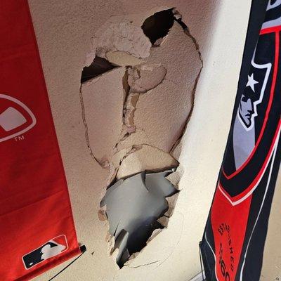 This is a hole in the drywall hidden behind a New England football banner..