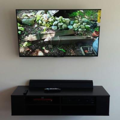 A 50 inch tv and a floating shelf mounted on the wall. All cables hidden in the wall.