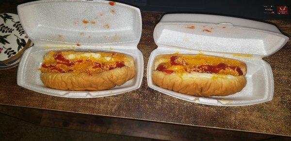 Two cheese hot dogs  with ketchup on it