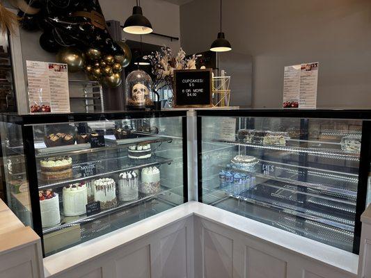 Display case of various cakes and some cupcakes