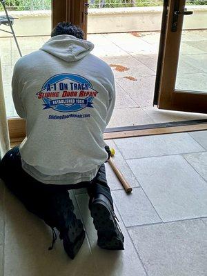 Kevin repairing a patio door while proudly displaying our company logo on the back of his sweatshirt. Note, established 1989.