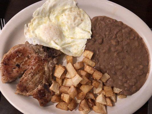 juicy porkchop with eggs, potatoes and beans