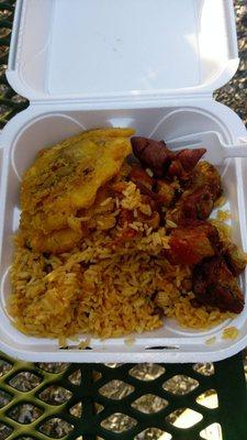 Yellow rice and pigeon peas, fried pork chunks, and fried green plantains