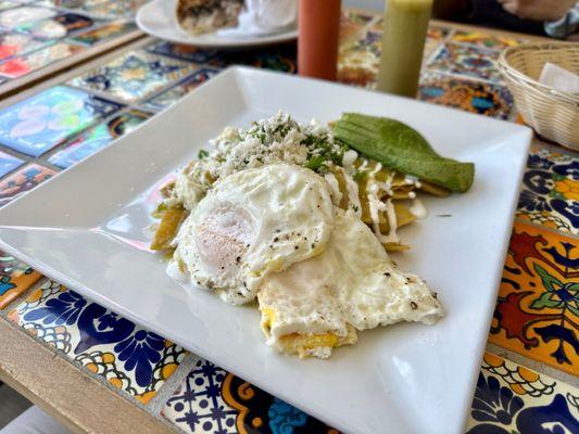 Salsa Verde Chilaquiles with Eggs - lightly fried corn tortillas, topped with spicy salsa verde, cotija cheese, and eggs