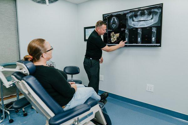 Dr. Jason B. Blundell explains to a patient the treatment plan at Coastal Jaw Surgery office in Trinity.