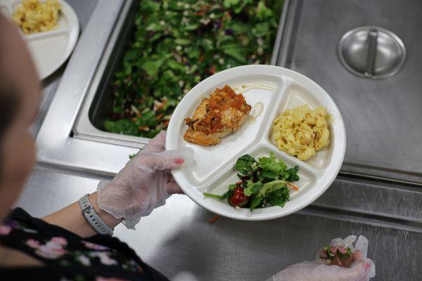 A volunteer plates food at Blanchet House